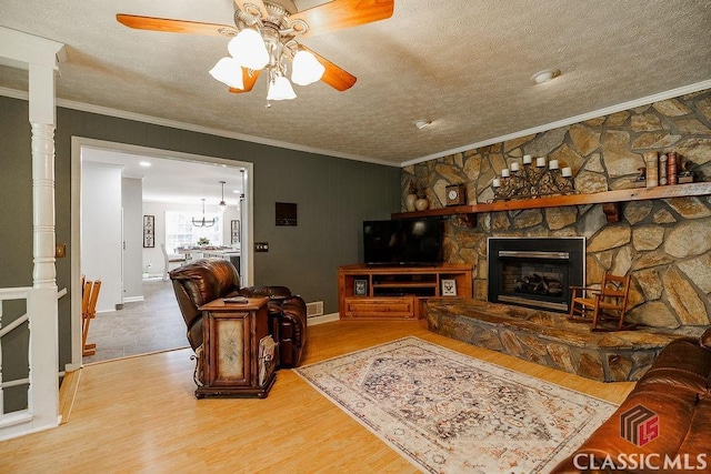 226 Baker St, Statham, GA 30666 - living room with ornamental molding, a textured ceiling, wood finished floors, a stone fireplace, and ceiling fan