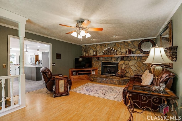 226 Baker St, Statham, GA 30666 - living room featuring a textured ceiling, wood finished floors, ornamental molding, a ceiling fan, and a fireplace
