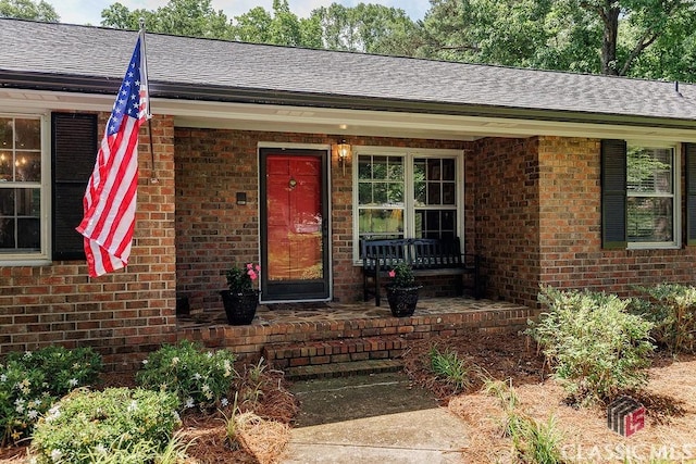 226 Baker St, Statham, GA 30666 - view of exterior entry featuring brick siding, a porch, and a shingled roof