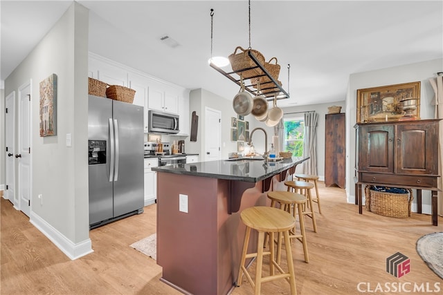 120 Peach Ln, Royston, GA 30662 - kitchen featuring stainless steel appliances, light wood-style floors, a kitchen bar, a center island with sink, and white cabinets