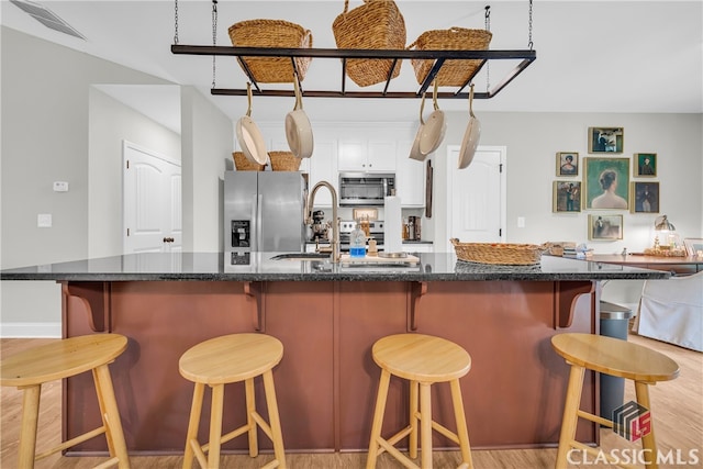 120 Peach Ln, Royston, GA 30662 - kitchen featuring stainless steel appliances, white cabinetry, light wood-type flooring, a breakfast bar area, and a spacious island