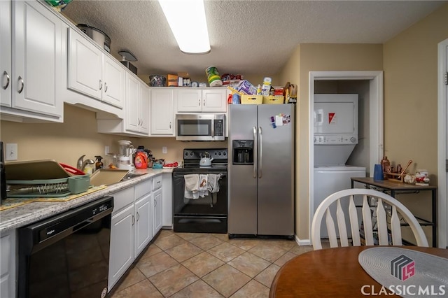 2165 S Milledge Ave Unit F4, Athens, GA 30605 - kitchen with black appliances, stacked washer / dryer, white cabinetry, light countertops, and light tile patterned flooring