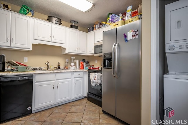 2165 S Milledge Ave Unit F4, Athens, GA 30605 - kitchen with black appliances, estacked washer and dryer, white cabinetry, light tile patterned floors, and light countertops