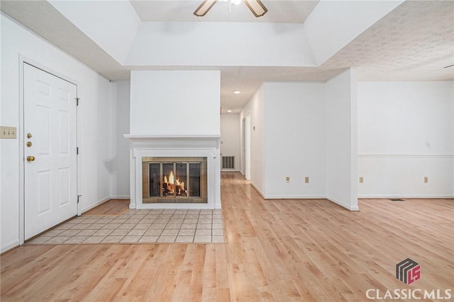 148 Hunters Crossing Rd, Athens, GA 30606 - unfurnished living room featuring light wood-style floors, ceiling fan, a glass covered fireplace, and a raised ceiling
