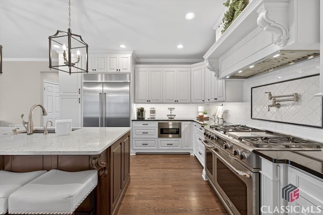 1232 Everton Pl, Cumming, GA 30041 - kitchen with high quality appliances, custom exhaust hood, light stone counters, tasteful backsplash, and white cabinets