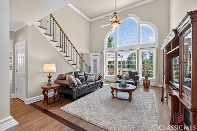 1232 Everton Pl, Cumming, GA 30041 - living room with stairway, crown molding, wood finished floors, ceiling fan, and a towering ceiling