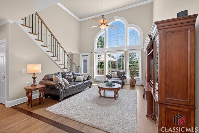 1232 Everton Pl, Cumming, GA 30041 - living room featuring stairs, crown molding, light wood-type flooring, a ceiling fan, and a high ceiling