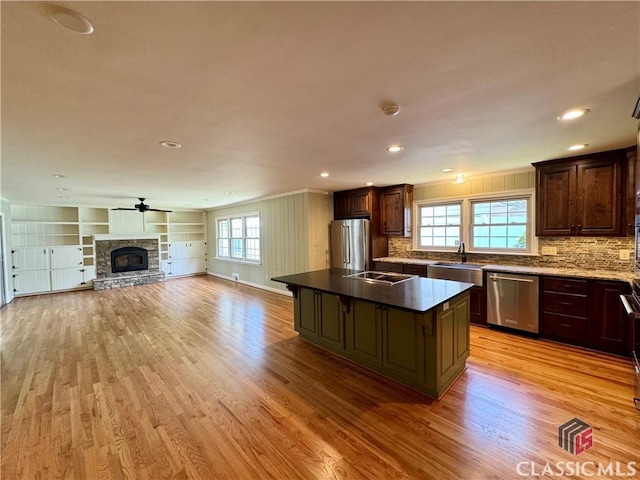 270 Riverhill Dr, Athens, GA 30606 - kitchen featuring appliances with stainless steel finishes, light wood finished floors, open floor plan, a stone fireplace, and a center island
