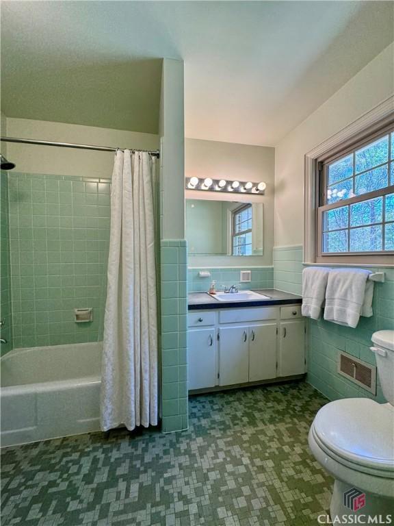270 Riverhill Dr, Athens, GA 30606 - full bathroom featuring tile walls, shower / bathtub combination with curtain, healthy amount of natural light, vanity, and wainscoting