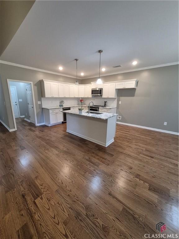 1070 Lane Creek Ter, Bishop, GA 30621 - kitchen with stainless steel microwave, crown molding, white cabinets, dark wood-style floors, and a center island with sink
