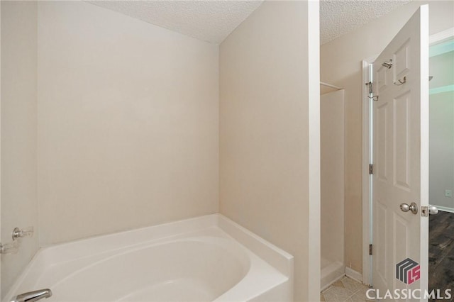 94 Pinewood Cir, Colbert, GA 30628 - bathroom with a textured ceiling, a bath, and a stall shower