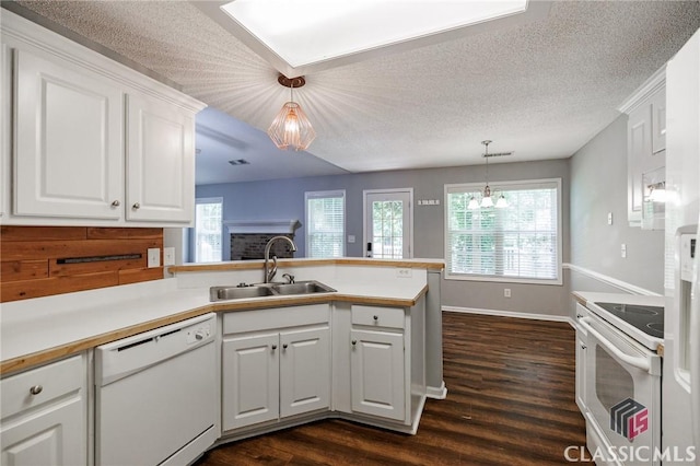 94 Pinewood Cir, Colbert, GA 30628 - kitchen featuring white appliances, dark wood finished floors, healthy amount of natural light, a peninsula, and a textured ceiling