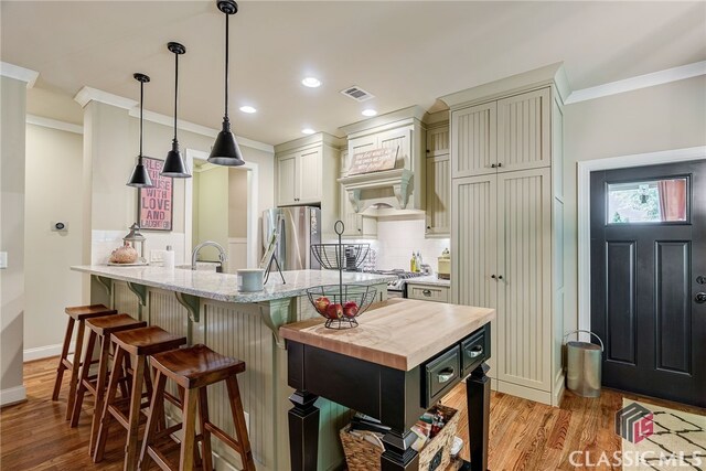 1640 Madison Ct, Bogart, GA 30622 - kitchen with freestanding refrigerator, ornamental molding, light wood-style floors, a kitchen breakfast bar, and backsplash