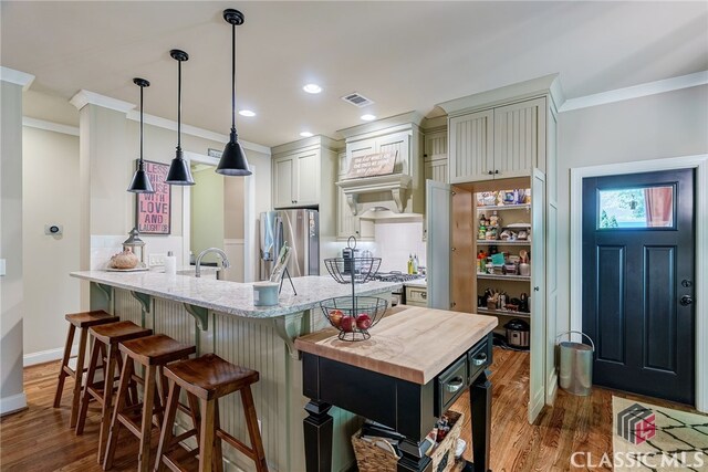1640 Madison Ct, Bogart, GA 30622 - kitchen with stainless steel fridge with ice dispenser, ornamental molding, dark wood-style floors, a kitchen bar, and decorative light fixtures