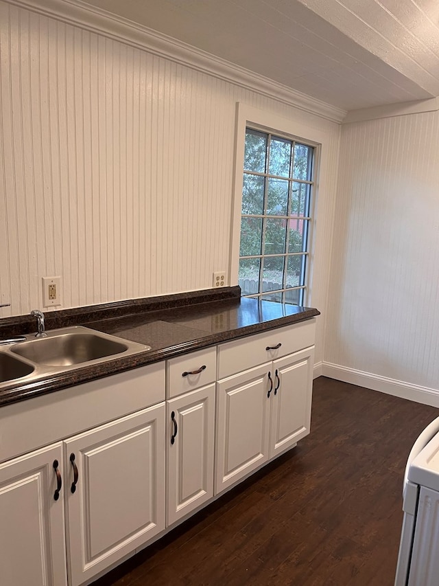 kitchen featuring a sink, white cabinetry, crown molding, baseboards, and dark wood-style flooring