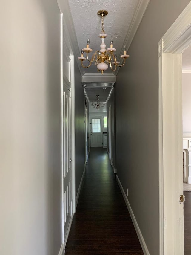 hall featuring baseboards, wood finished floors, a chandelier, and crown molding