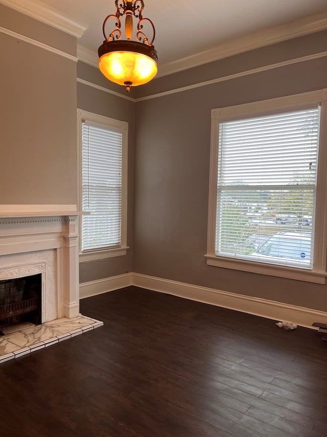 unfurnished living room featuring dark wood-style floors, a healthy amount of sunlight, and ornamental molding