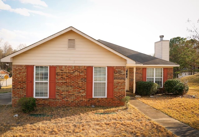 ranch-style home featuring a chimney and brick siding