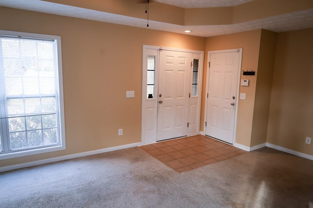 entrance foyer with carpet, tile patterned flooring, plenty of natural light, and baseboards