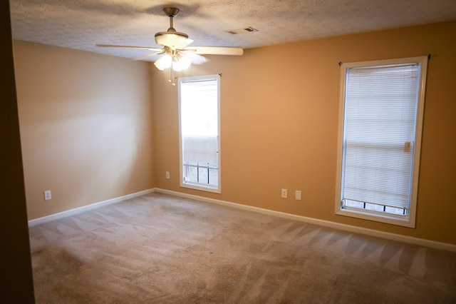 spare room with a textured ceiling, carpet, visible vents, and baseboards