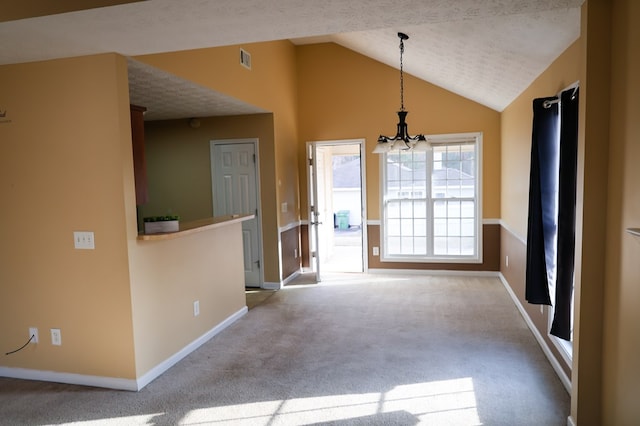 unfurnished dining area with a textured ceiling, carpet flooring, visible vents, vaulted ceiling, and an inviting chandelier