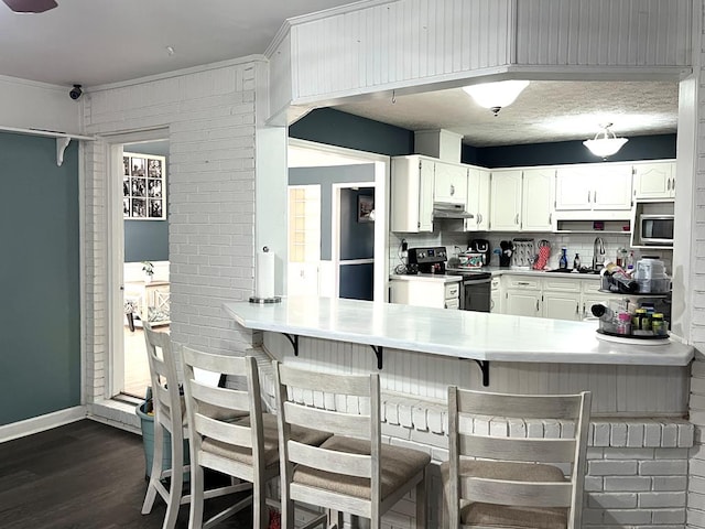 kitchen featuring electric stove, dark wood finished floors, white cabinets, a sink, and a peninsula