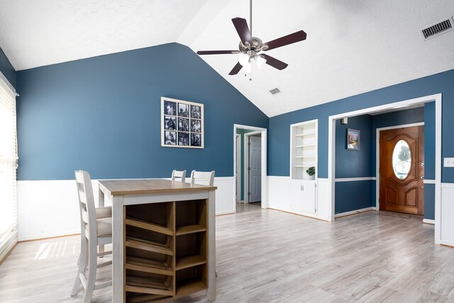 interior space with wainscoting, wood finished floors, visible vents, and built in features