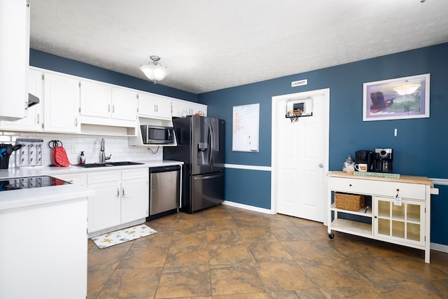 kitchen featuring stainless steel appliances, light countertops, backsplash, white cabinets, and a sink