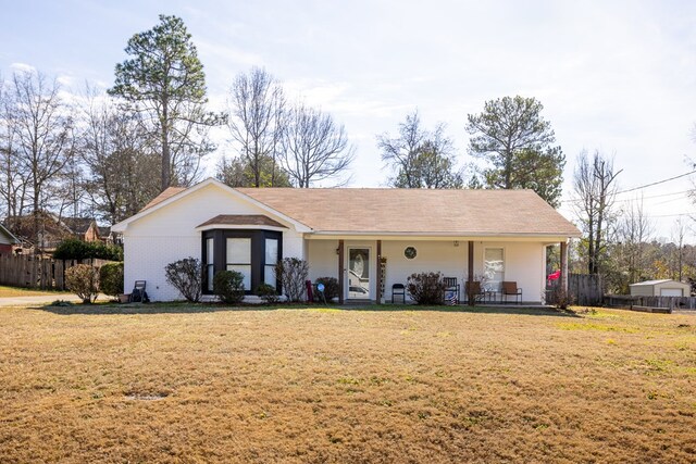 ranch-style house featuring brick siding, covered porch, fence, and a front yard