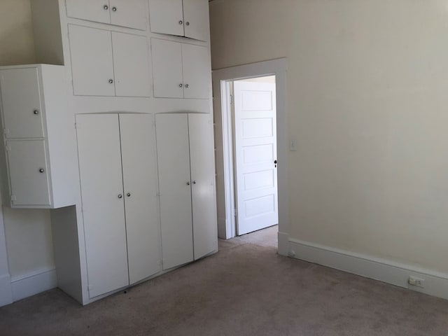 unfurnished bedroom with a closet and light colored carpet