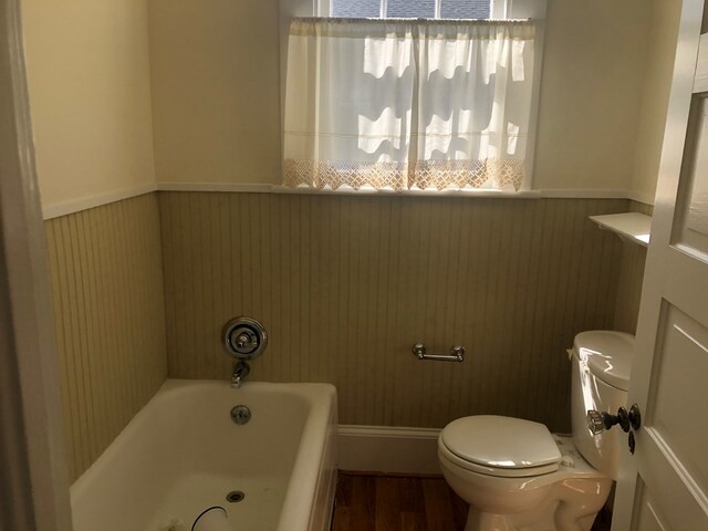 bathroom with wood walls, toilet, wood-type flooring, and a bath