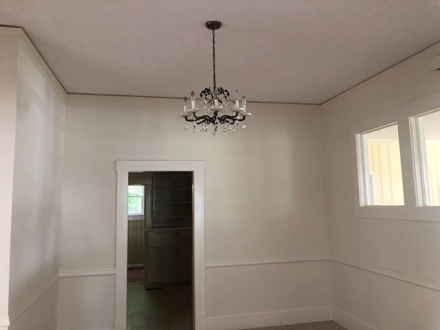 unfurnished room featuring a chandelier and a textured ceiling