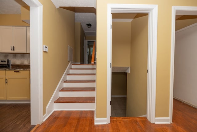 stairs with hardwood / wood-style floors and a textured ceiling