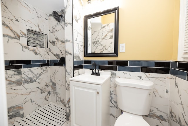 bathroom featuring tiled shower, vanity, toilet, and tile walls