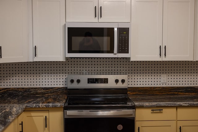 kitchen with decorative backsplash, appliances with stainless steel finishes, white cabinets, and dark stone counters