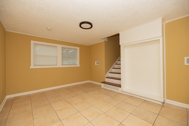 unfurnished room with a textured ceiling, ornamental molding, and light tile patterned flooring