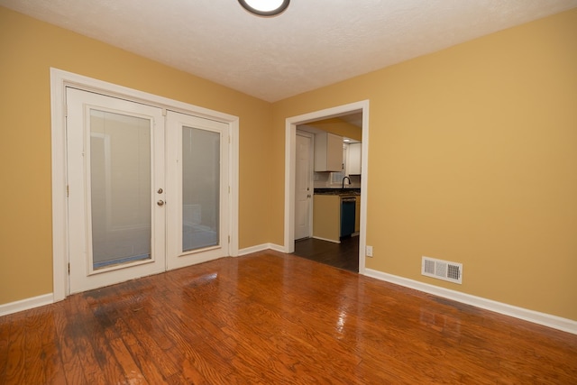 spare room featuring hardwood / wood-style floors, a textured ceiling, french doors, and sink