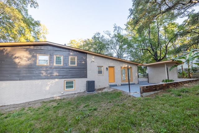 rear view of house featuring a yard, cooling unit, and a patio area