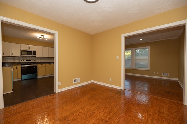 unfurnished living room with a textured ceiling and dark wood-type flooring