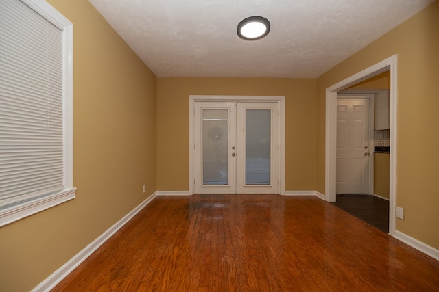 unfurnished room featuring french doors, a textured ceiling, and dark wood-type flooring