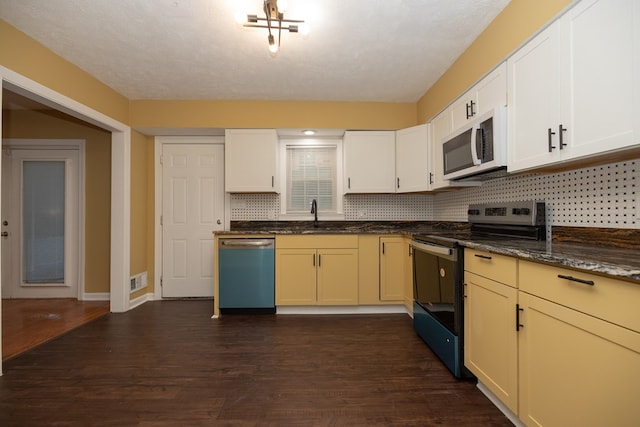 kitchen featuring dark hardwood / wood-style floors, dark stone countertops, sink, and stainless steel appliances