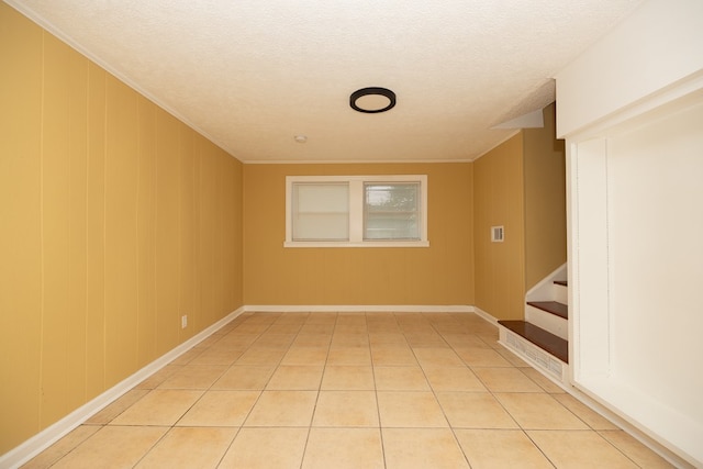 tiled spare room with a textured ceiling and crown molding