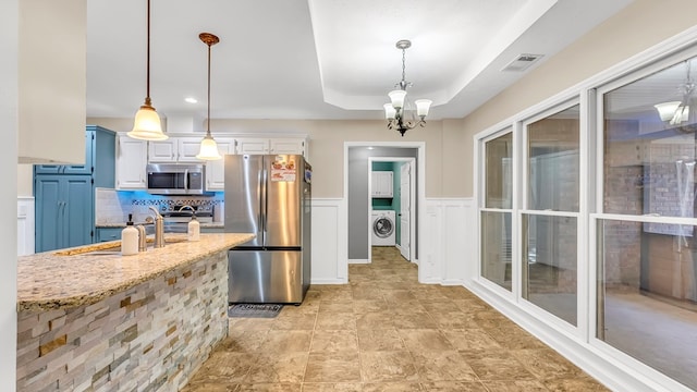 kitchen with white cabinets, appliances with stainless steel finishes, decorative light fixtures, and an inviting chandelier