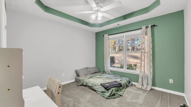 bedroom with carpet, a raised ceiling, and ceiling fan