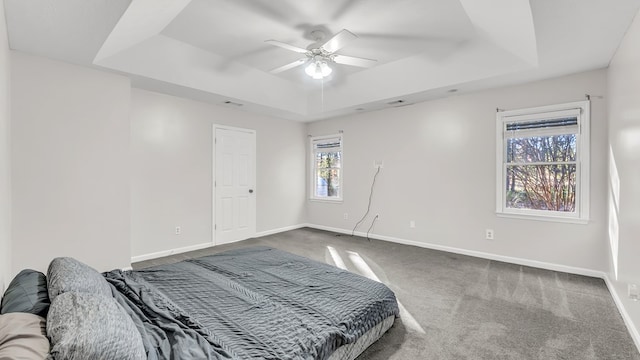 carpeted bedroom with a tray ceiling and ceiling fan