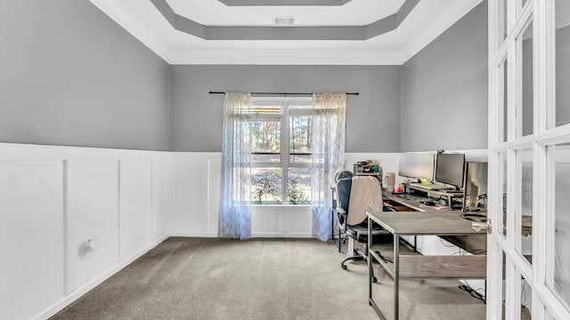 home office with a raised ceiling and light colored carpet