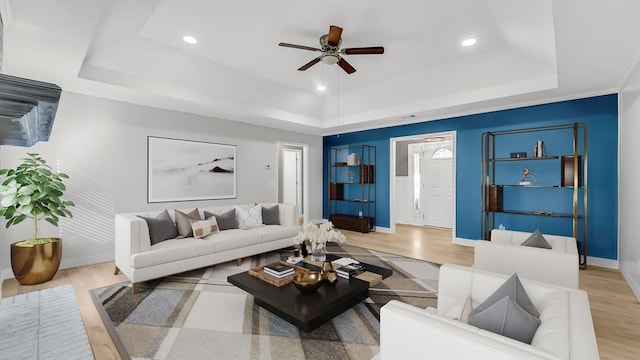 living room with a tray ceiling, ceiling fan, and light hardwood / wood-style floors