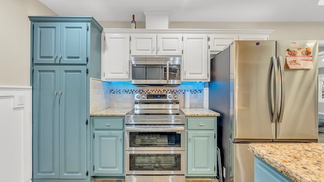 kitchen with backsplash, light stone countertops, white cabinets, and stainless steel appliances