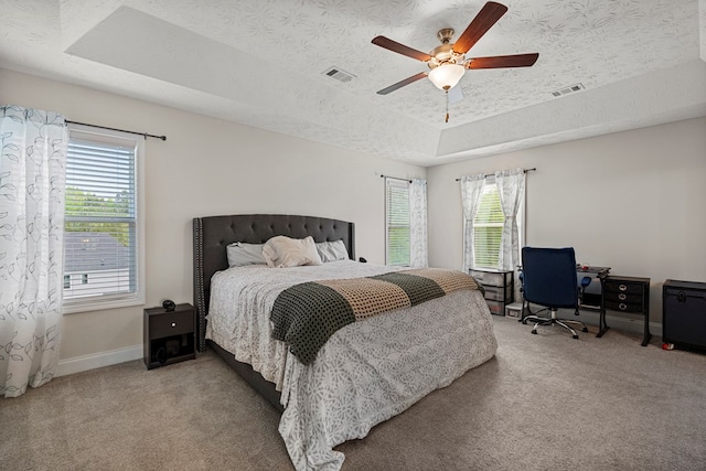 bedroom with a raised ceiling, visible vents, carpet flooring, and baseboards