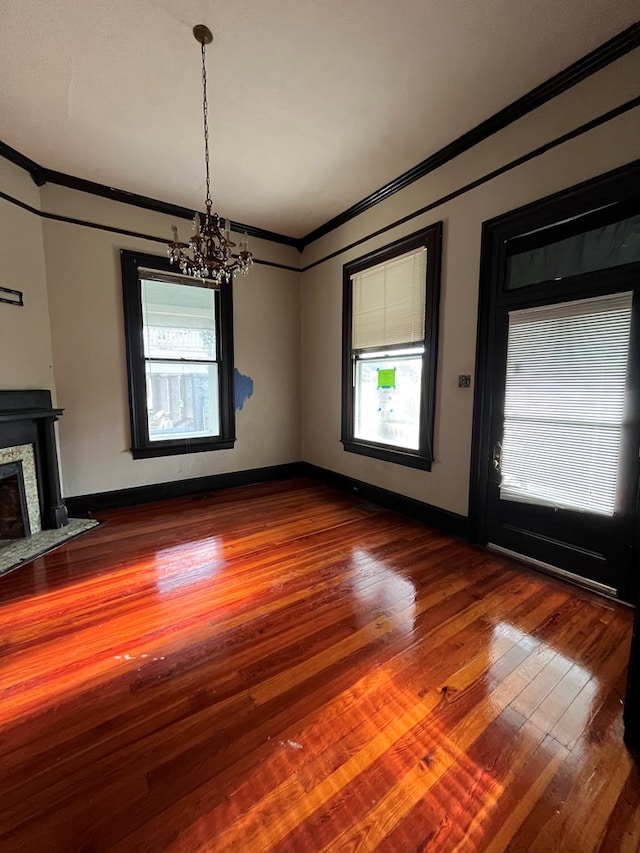 unfurnished living room with a wealth of natural light, hardwood / wood-style floors, and a notable chandelier